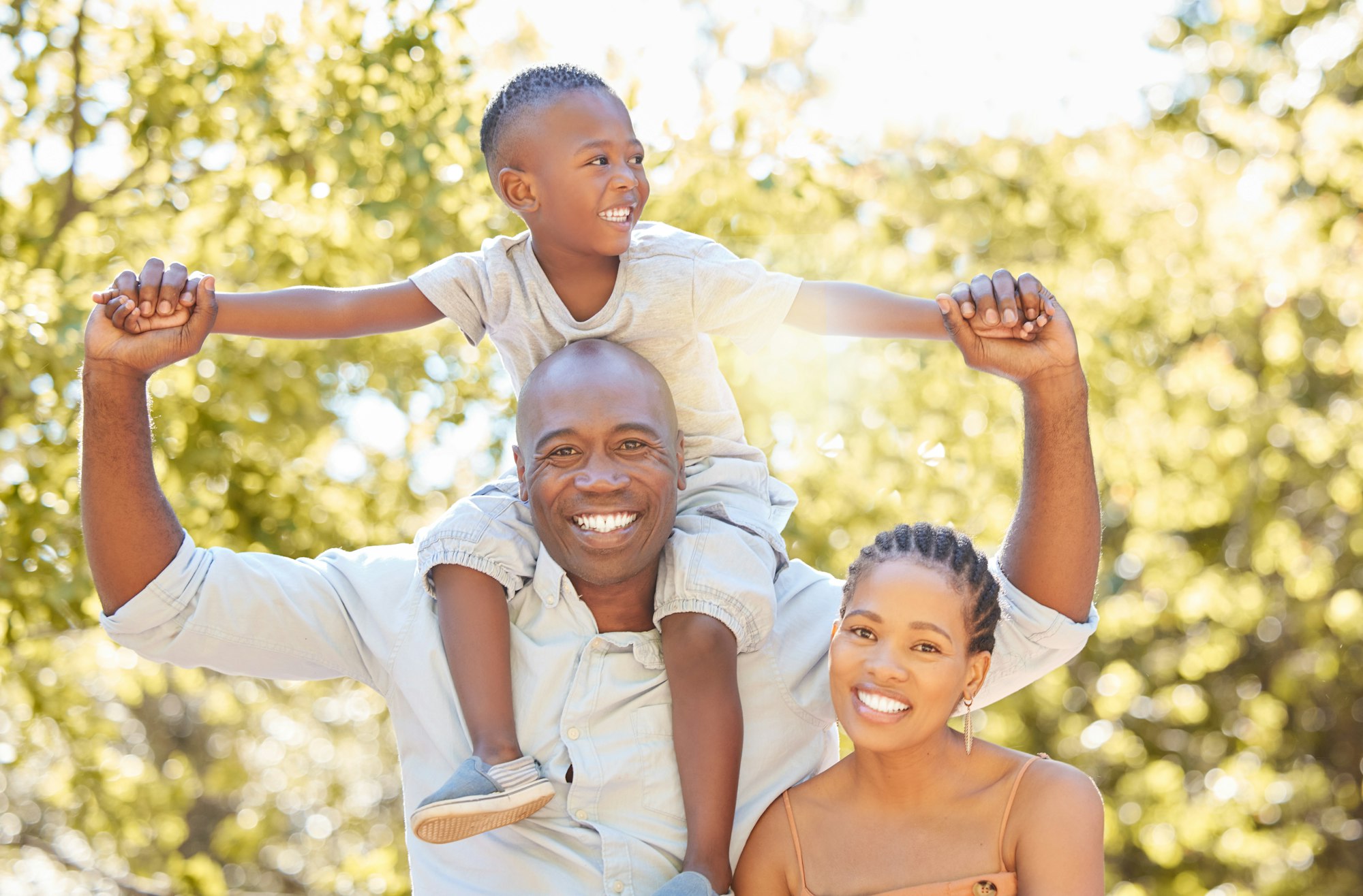 Portrait happy african american family of three spending quality time together in the park during s