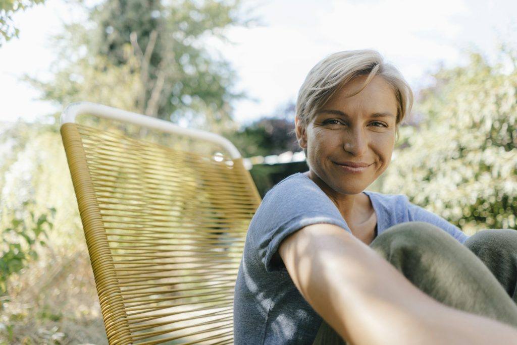 Portrait of smiling woman sitting in garden on chair